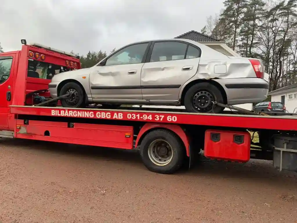 Bärgningsbil hämtar skrotbil från parkering för gratis transport till bilskrot och återvinning.