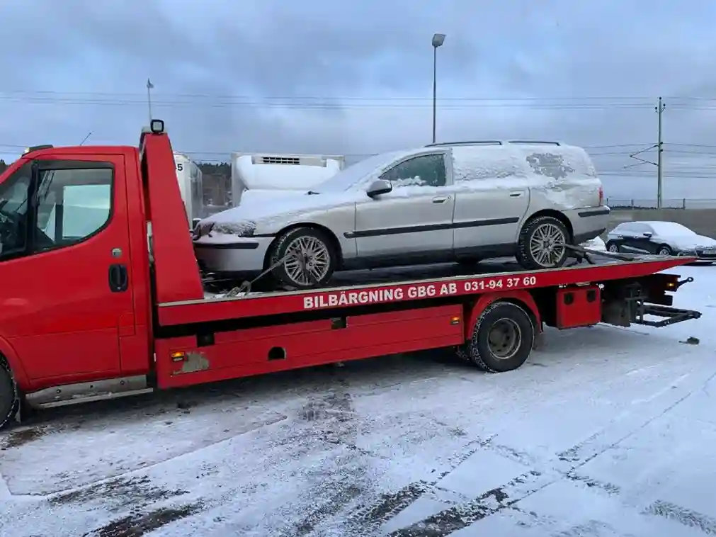 Bärgningsbil hämtar skrotbil från uppfart för transport till närliggande bilskrot och återvinning.