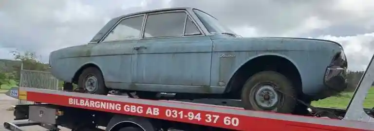 Bil med trasig motor lastas på bärgningsbil för transport till bilskrot.